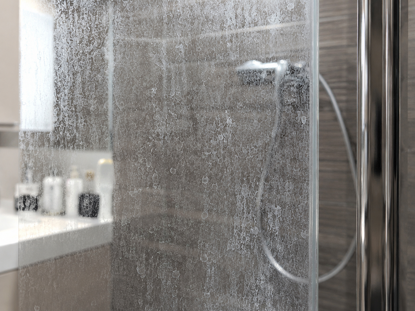 Hard water scale and cloudy mineral build-up on a glass shower door.